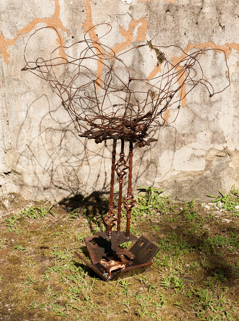 Welded steel sculpture of nest on pedestal