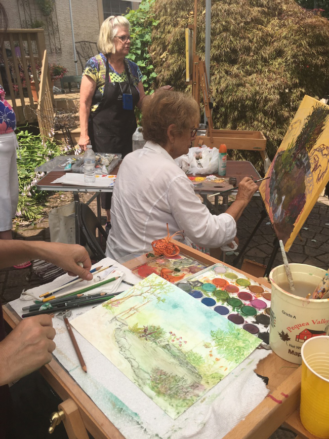 Side by side, Delona (here is her hand, her palette and her lovely watercolor), Joan (top) and Bobbi share some tips, feedback, suggestions and, shade under a tent.
